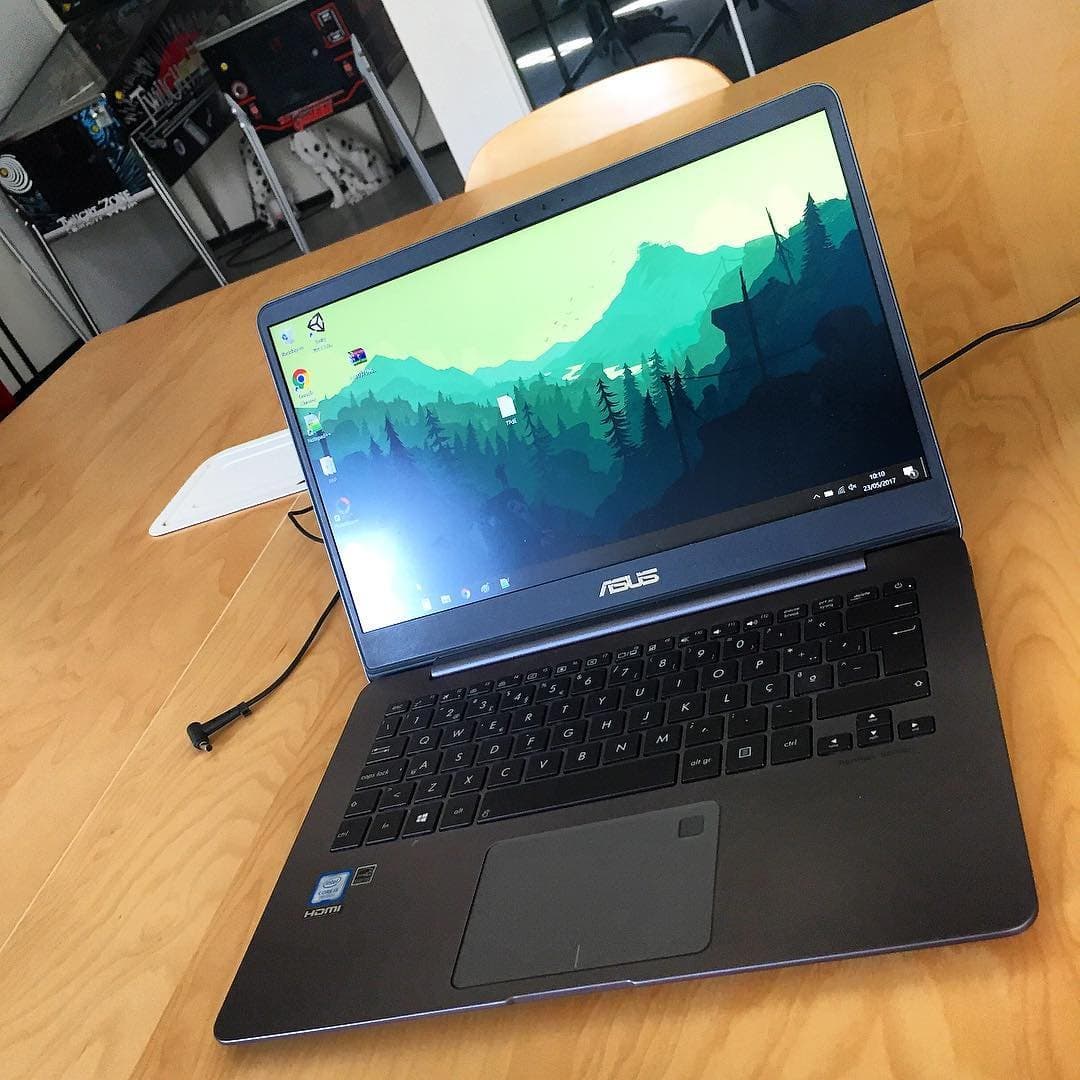 A laptop on a wooden table at AG Films, with pinball machines behind it