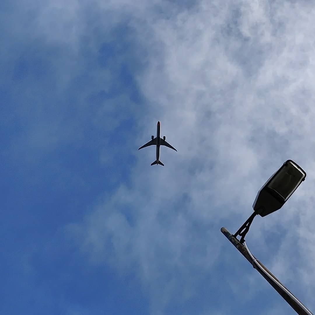 An airliner crossing a blue sky, seen from below